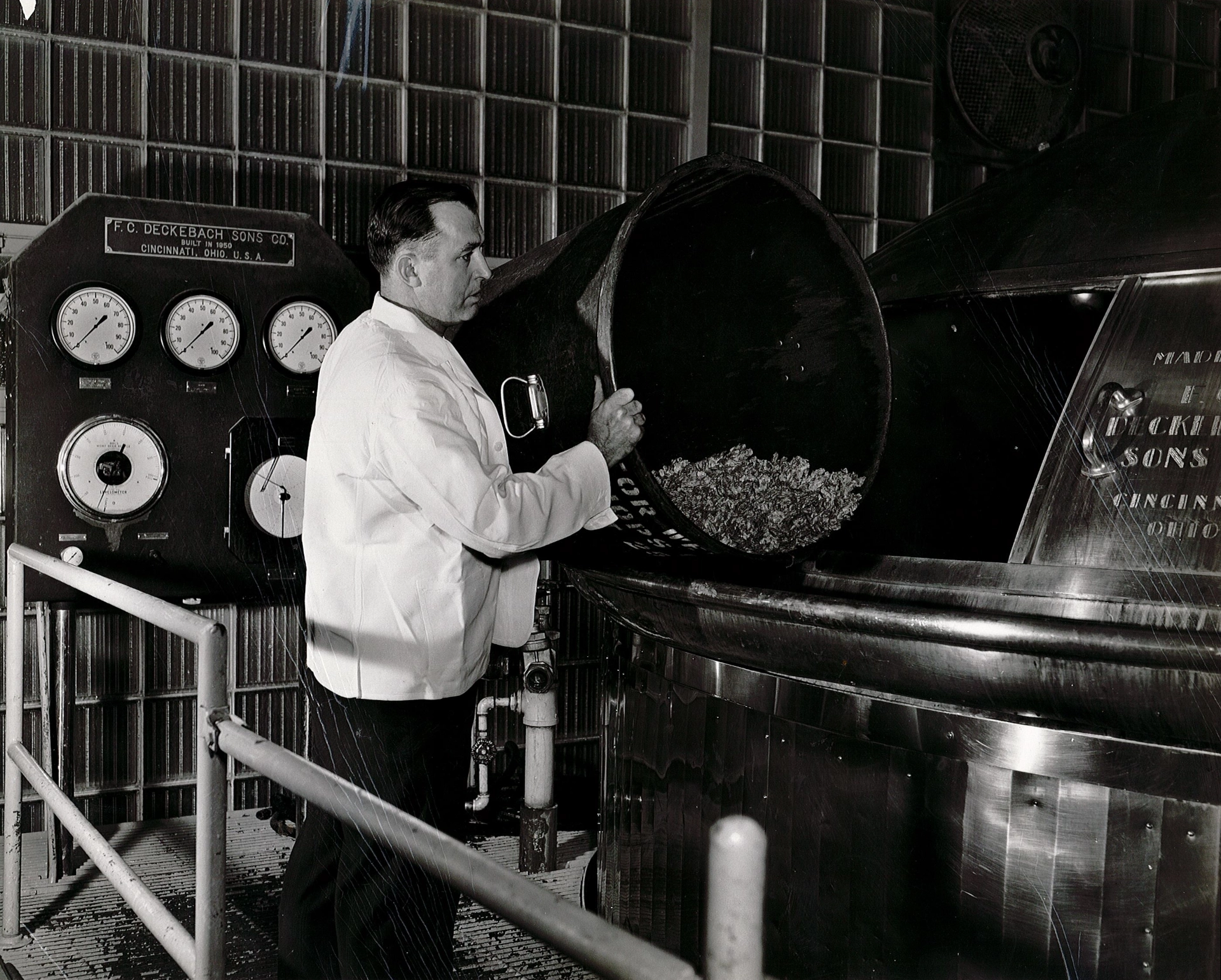 An operator adding hops to a brew kettle